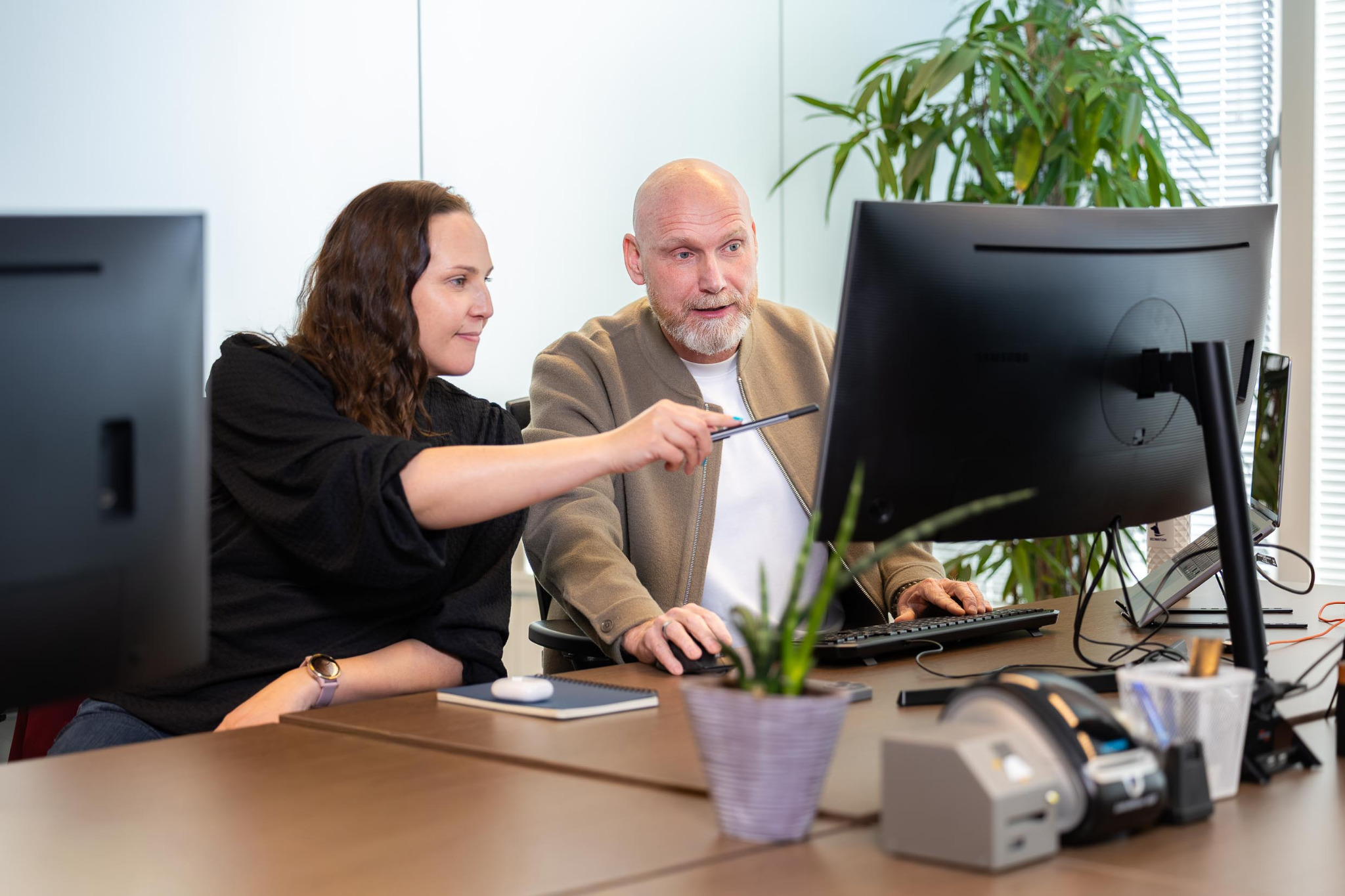 Two SECWATCH colleagues discuss an assessment at a computer screen.